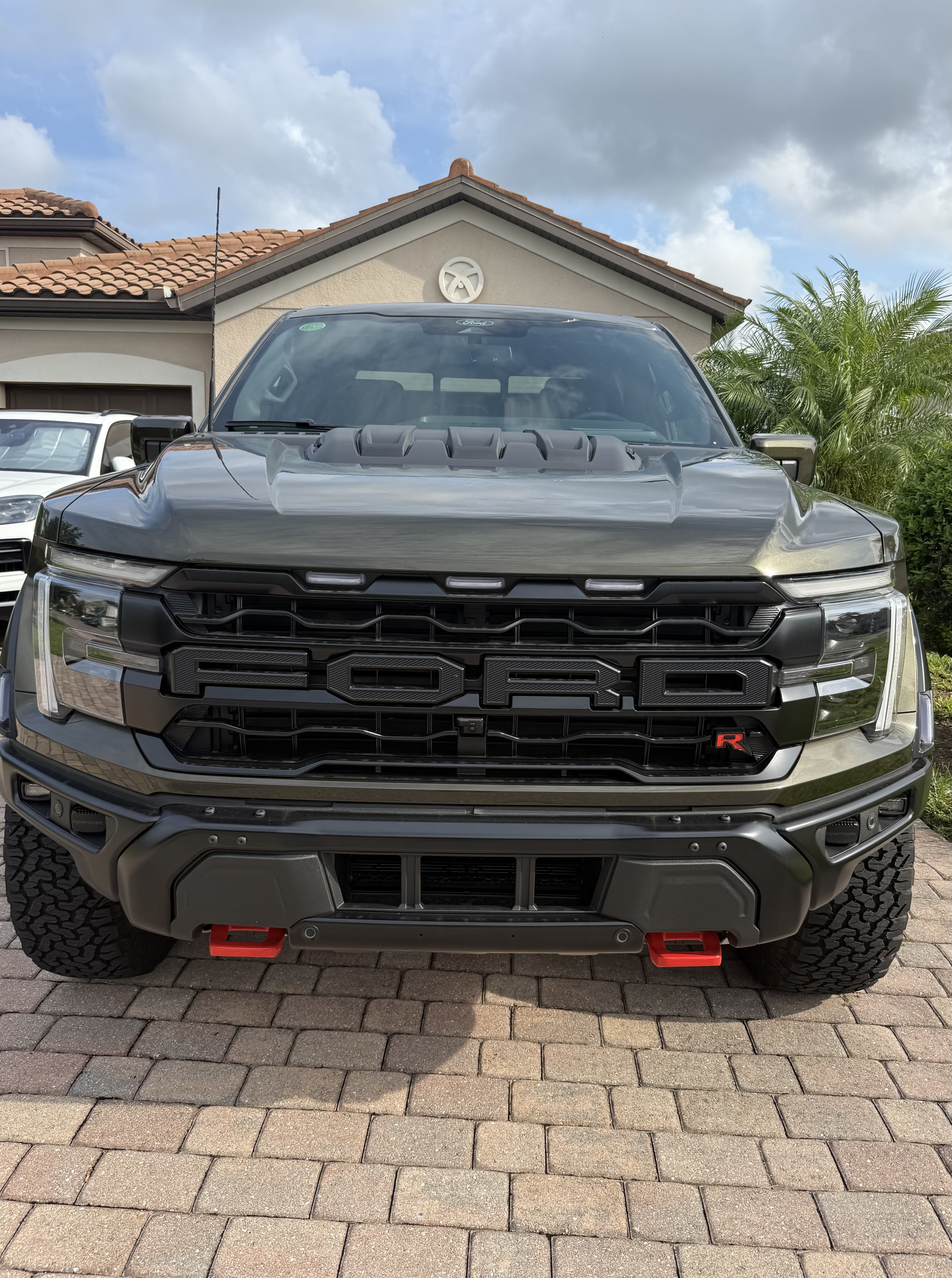 Head on view of the 2026 Ford F 150 Raptor R grille and red recovery hooks